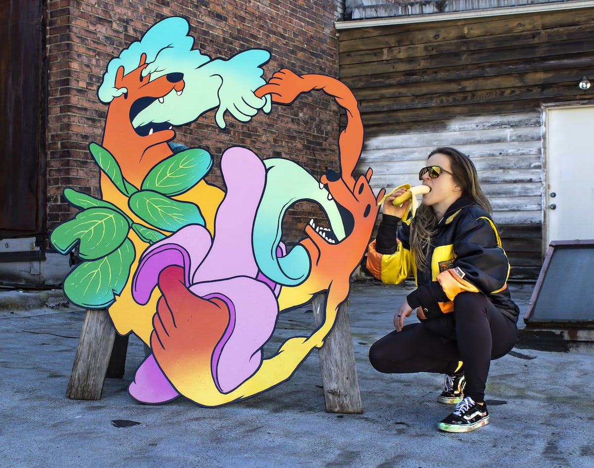 Woman crouching in front of an illustration of two dogs
