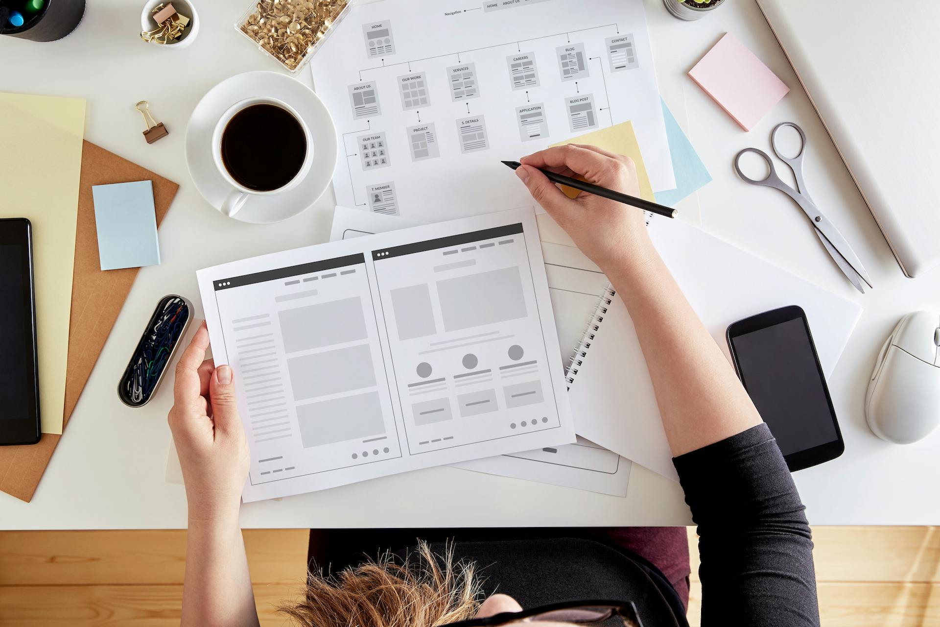 Overhead stock photo of a woman at a desk drafting notes on her web design UX/UI and the page flow