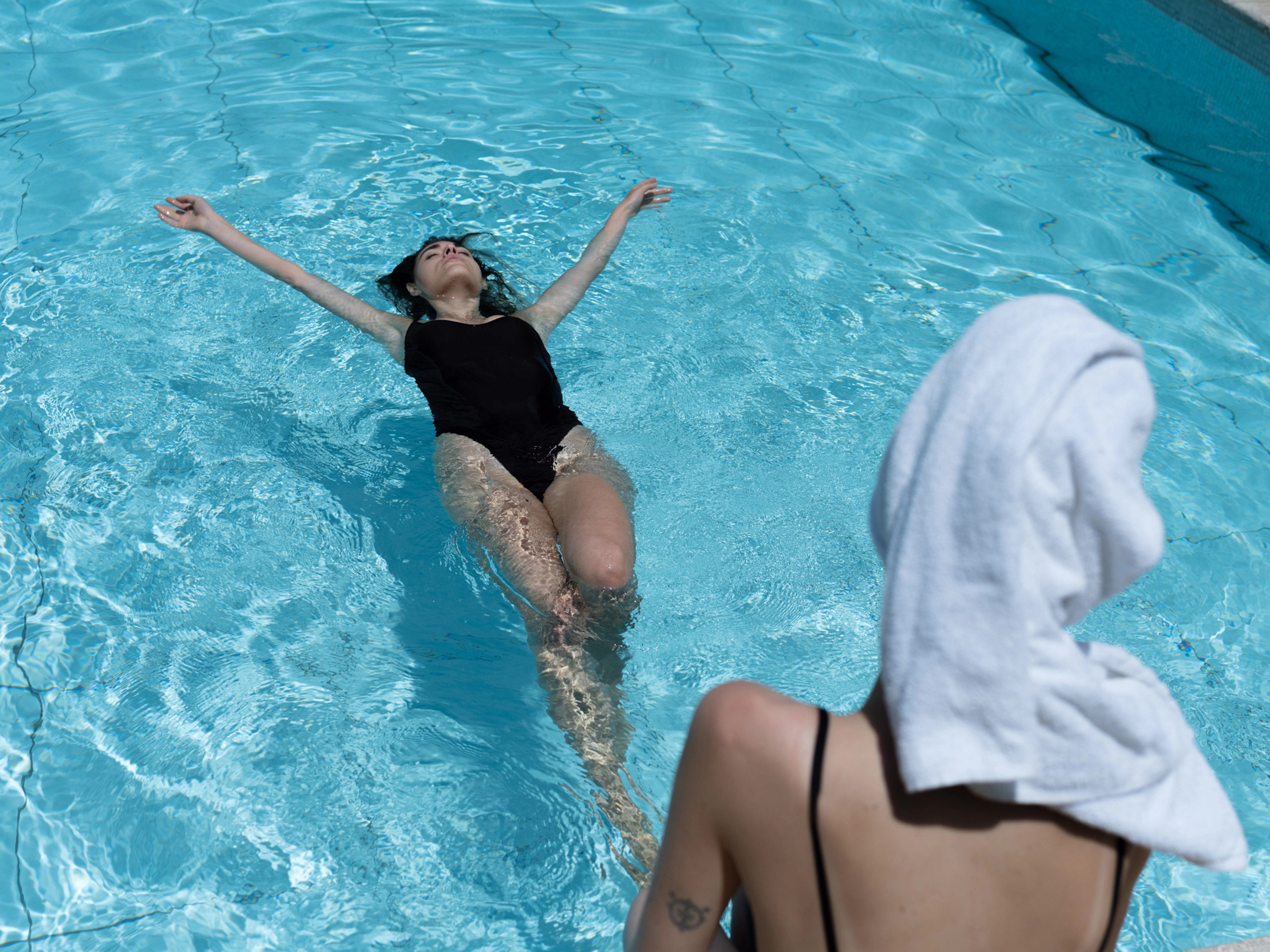 Woman floating in a clear blue swimming pool at La Fonte luxury venue in Italy