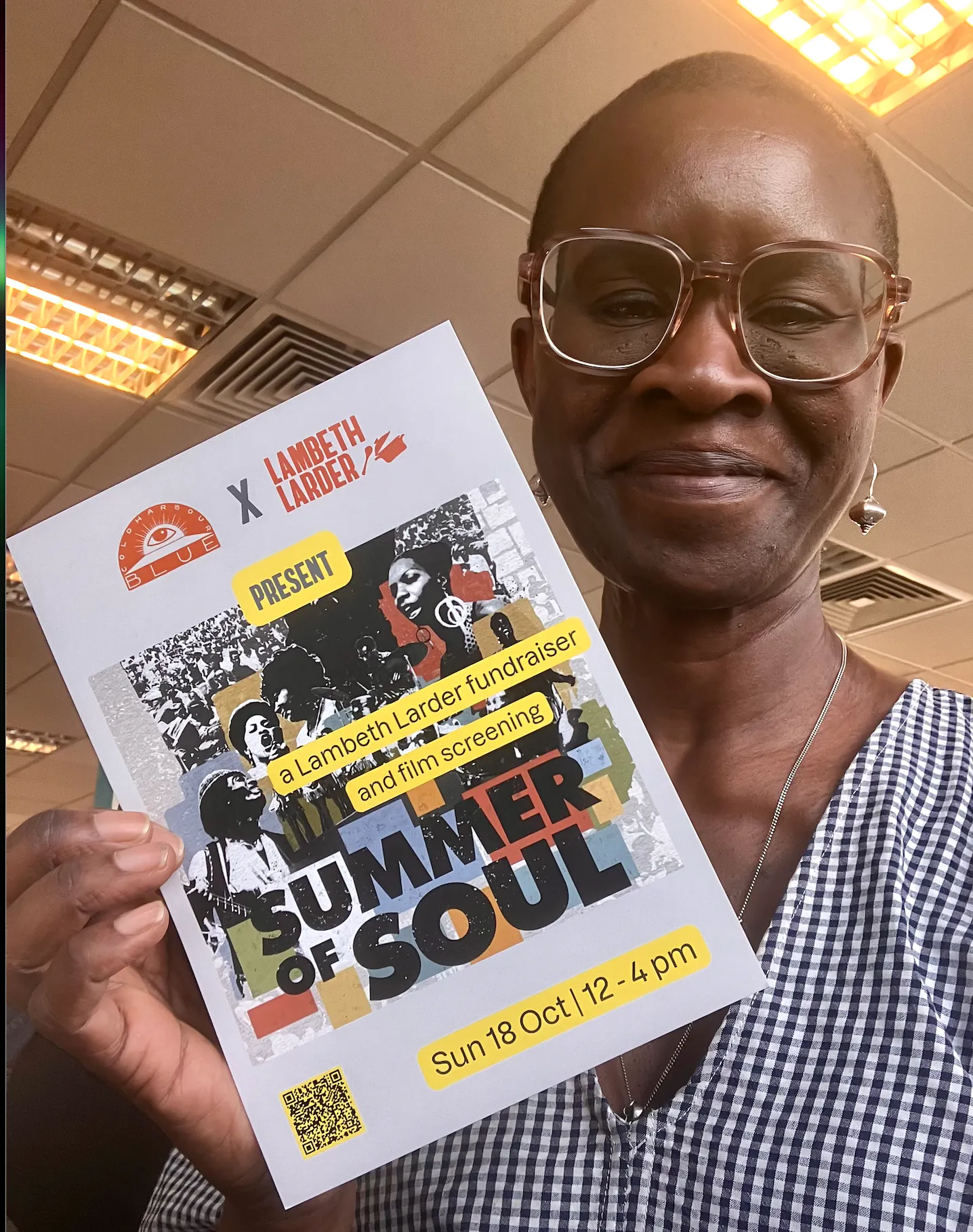 Black woman holding colourful flyer in hand smiling at camera.