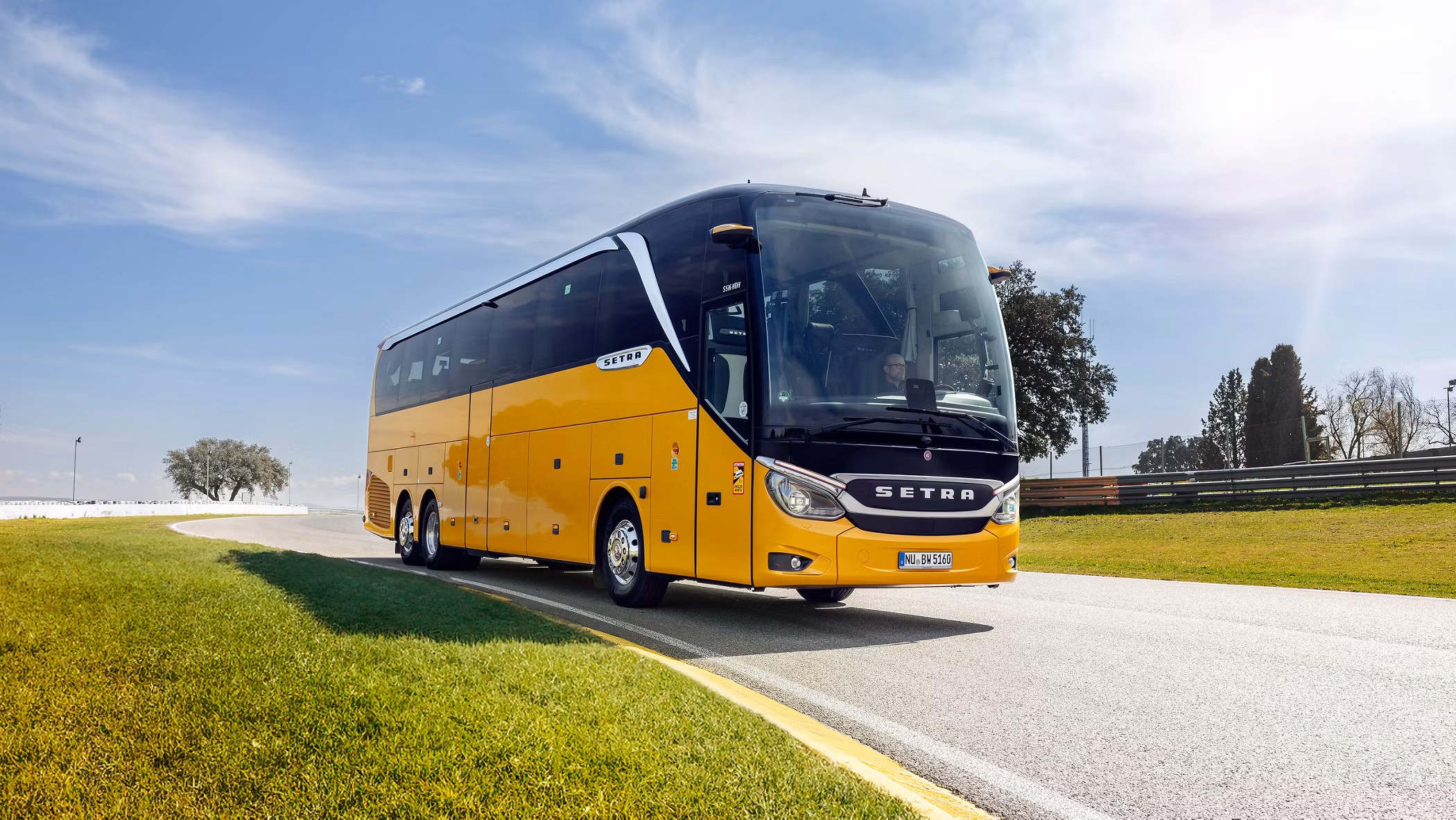 Setra hópferðabíll á ferðinni í góðu veðri, gul á litinn