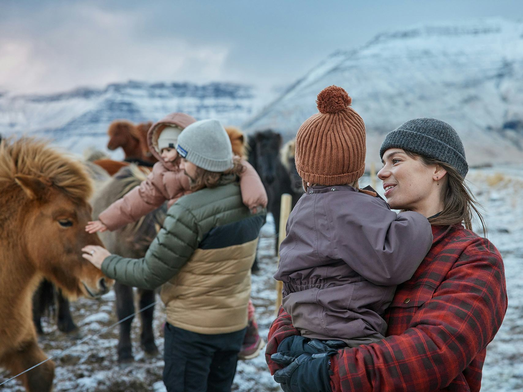 Fjölskylda skoðar hesta um vetur
