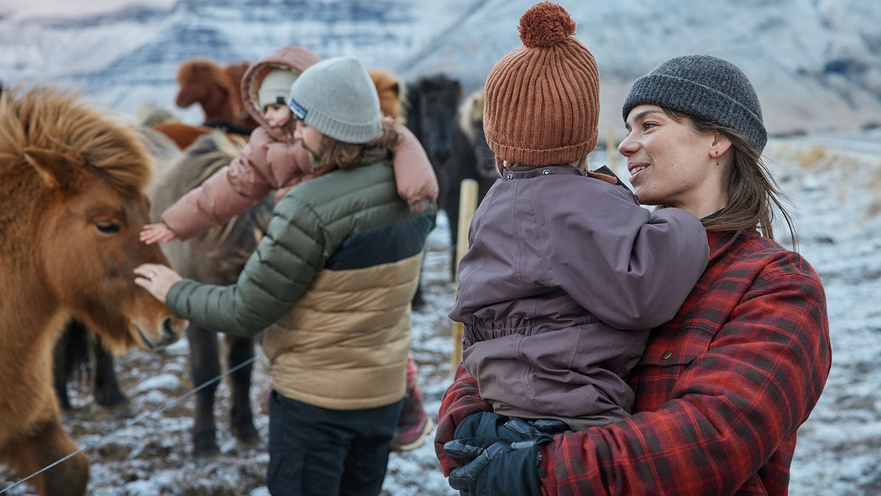 Fjölskylda skoðar hesta um vetur