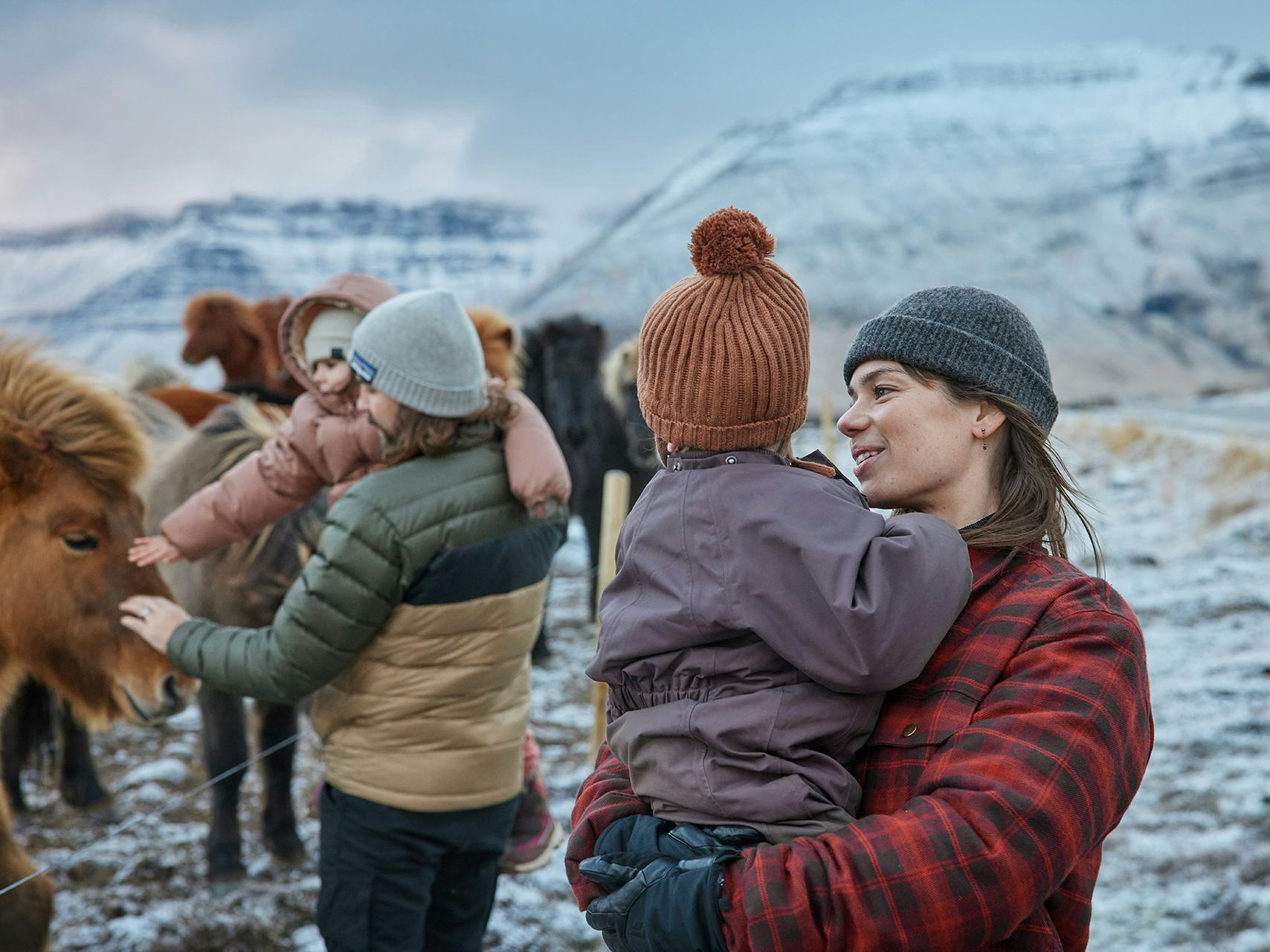 Fjölskylda skoðar hesta um vetur