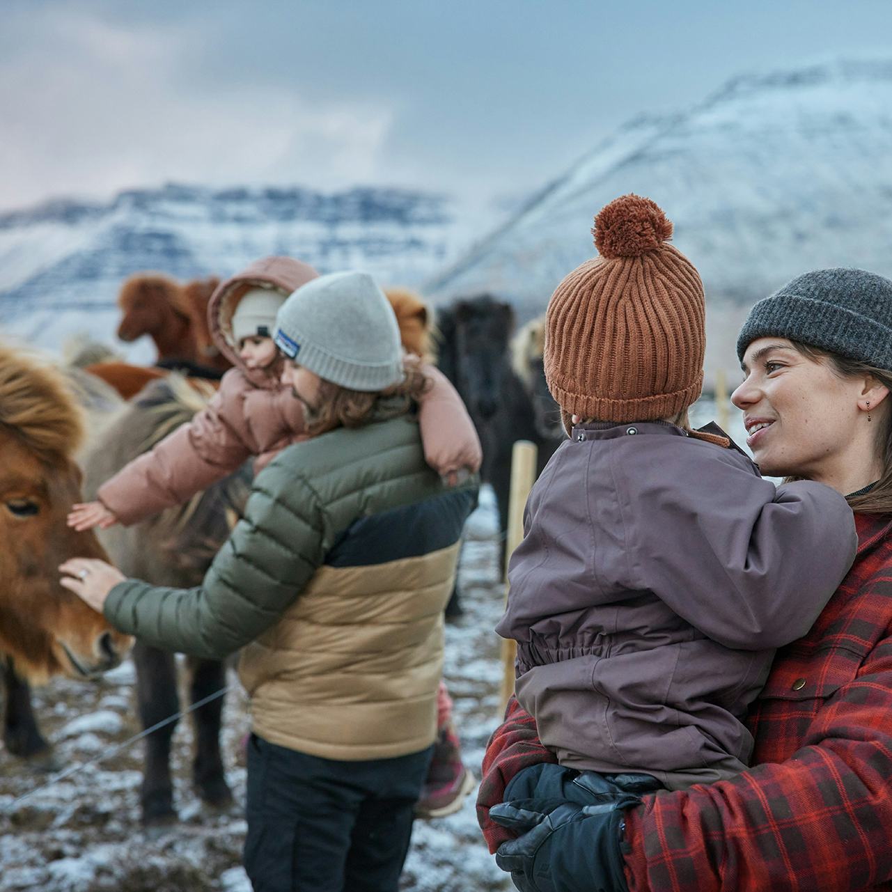 Fjölskylda skoðar hesta um vetur