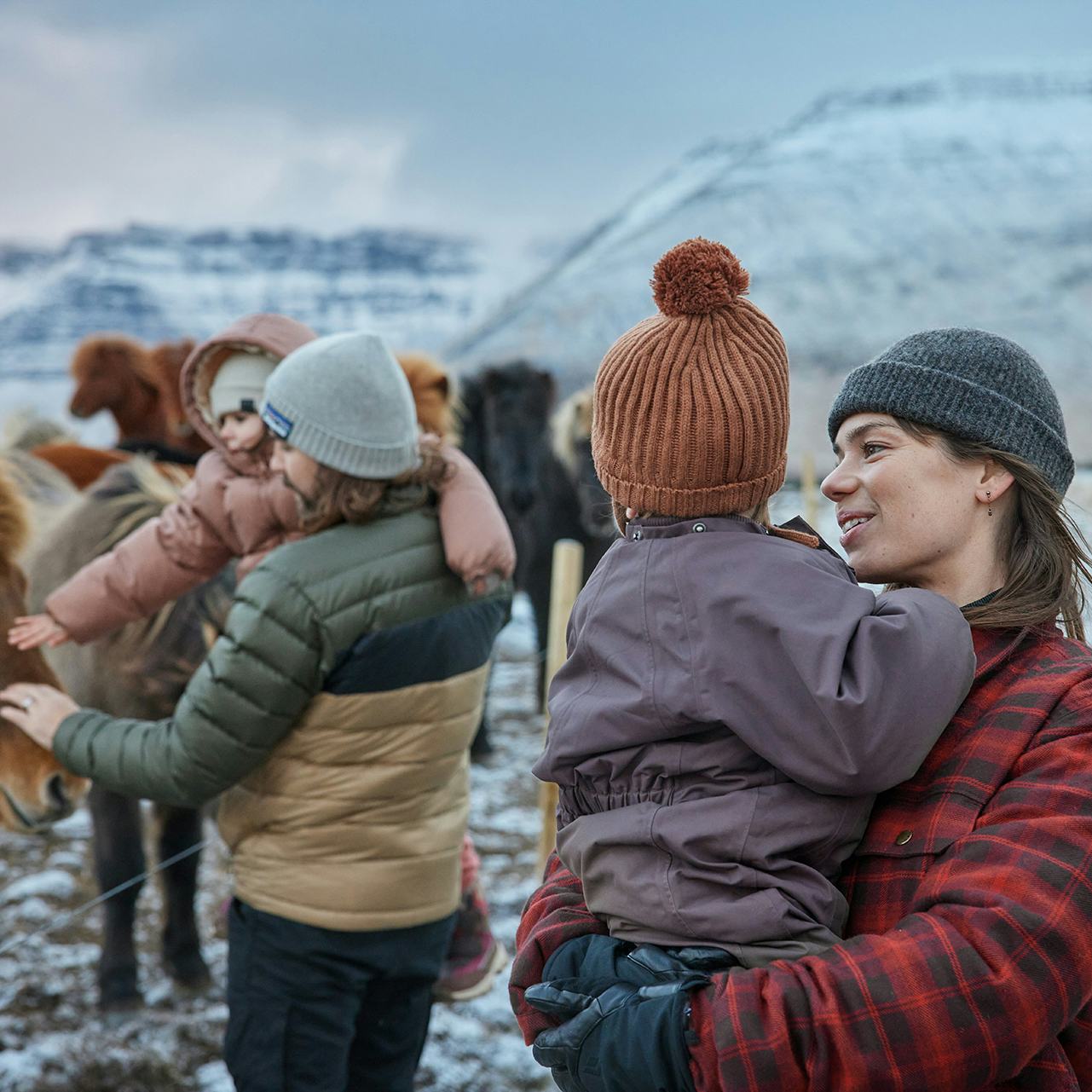 Fjölskylda skoðar hesta um vetur