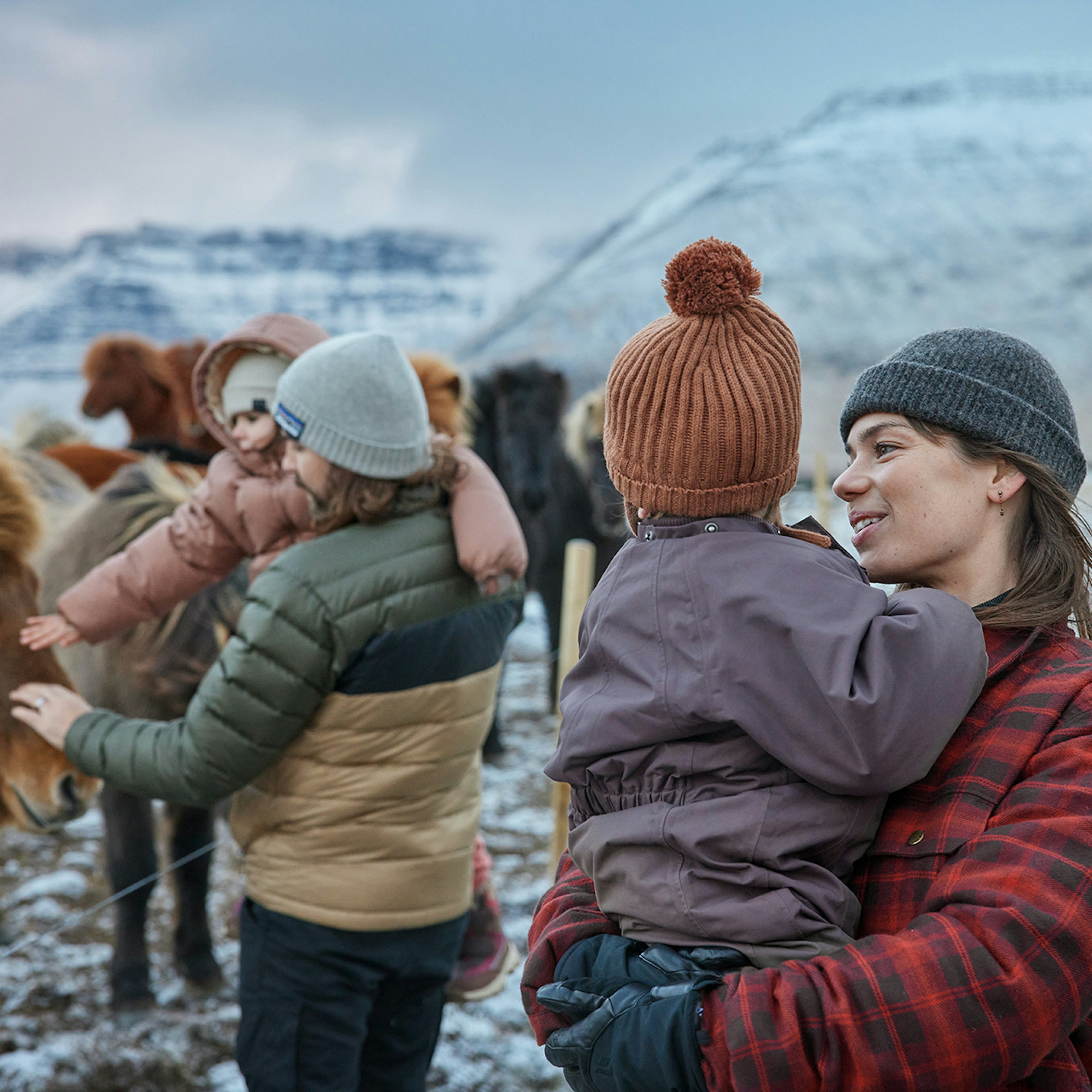 Fjölskylda skoðar hesta um vetur