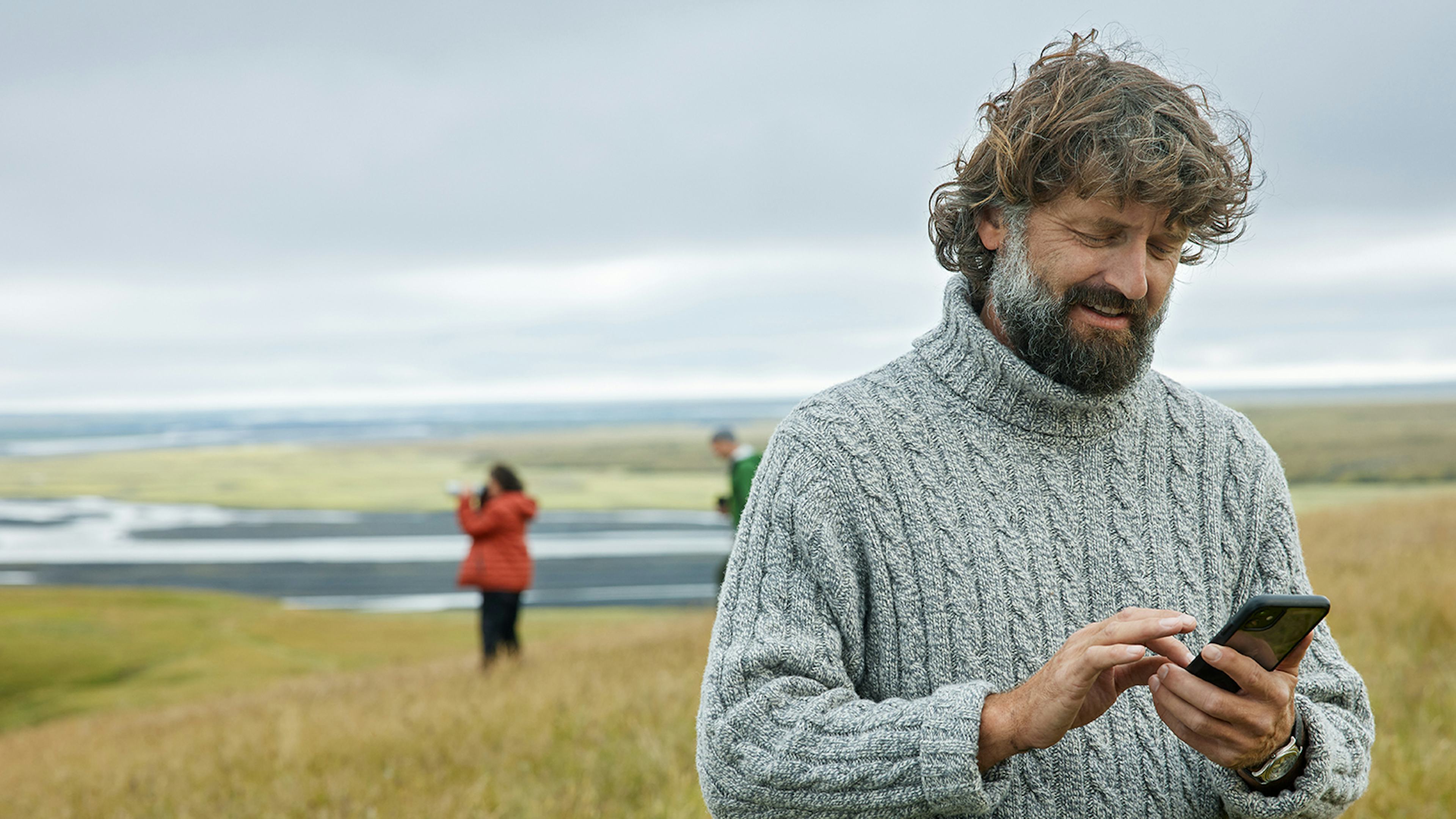 Maður með síma úti í náttúrunni