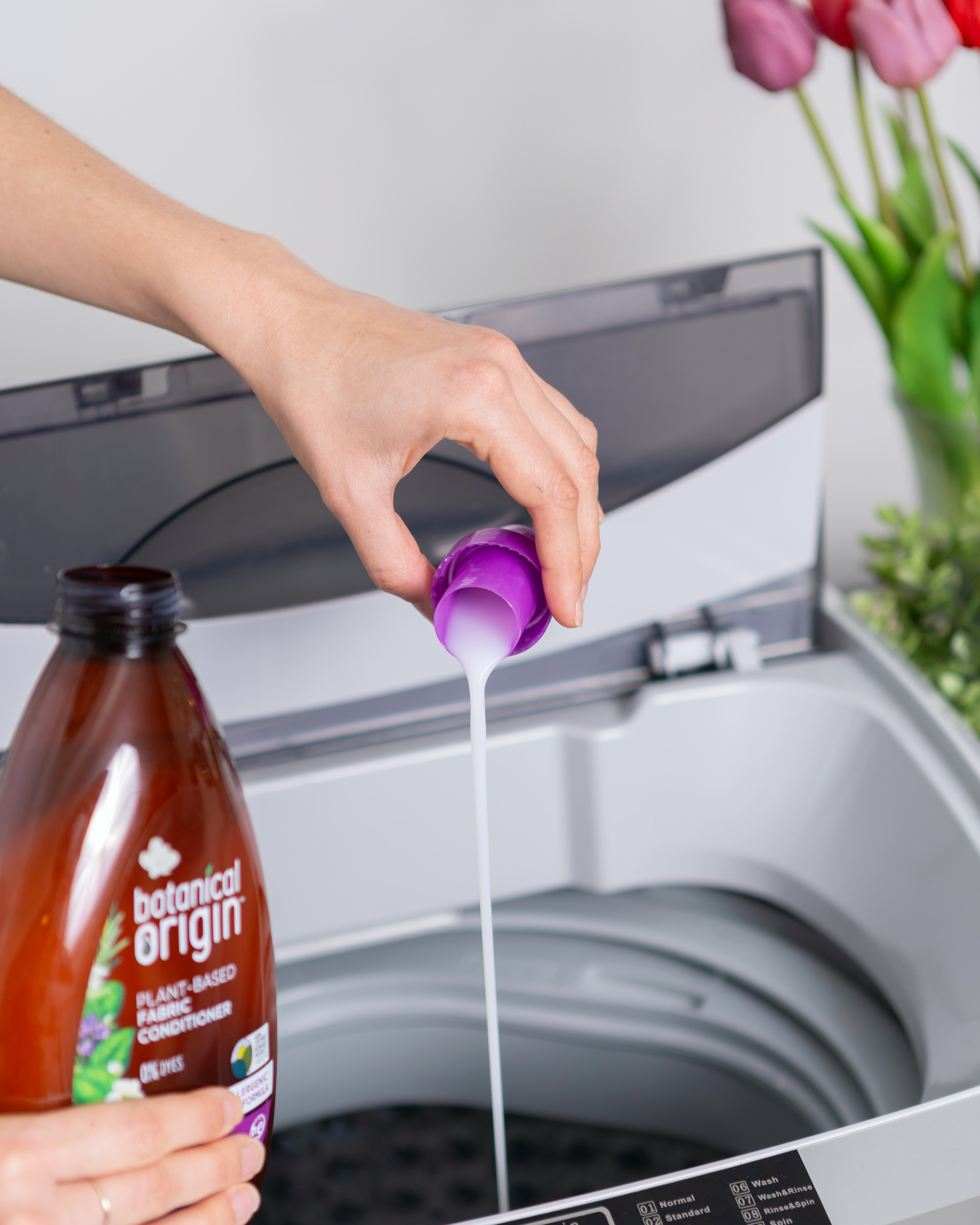 Person Pouring Detergent Into A Washing Machine.