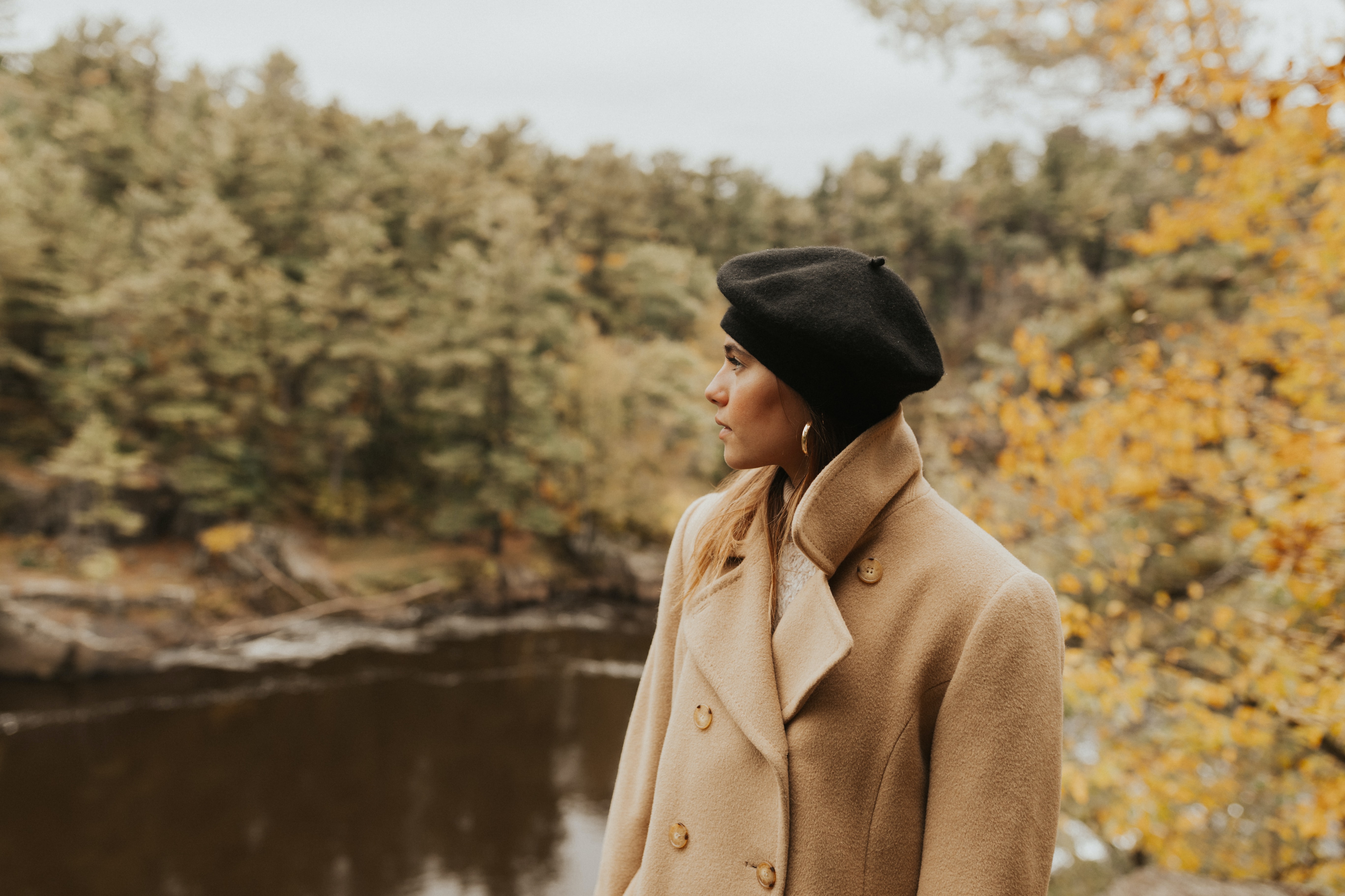 Woman wearing a beige coat in a forest