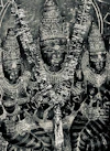 Black-and-white photograph of an ornate multi-faced Hindu deity statue with tall carved crowns and heavy jewelry.