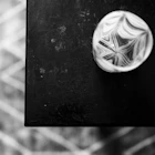 Overhead view of a glass tumbler with a starburst base pattern on a dark tabletop.