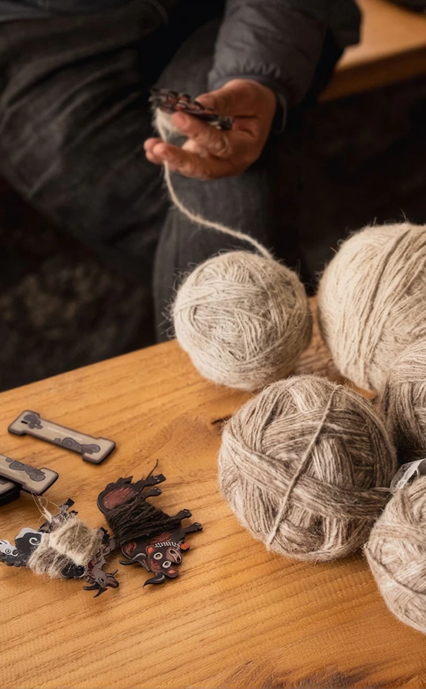 Weathered hands parting dense grey fleece to reveal bright, crimped white wool underneath.