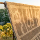 Lavor Ombra rug draped over a metal bar in warm outdoor light.