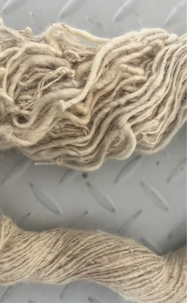 Two cream fiber samples on metal: loose, crimped fleece beside tightly twisted yarn.