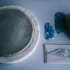 Cracked circular clay piece with blue test tiles arranged on a smooth gray surface.