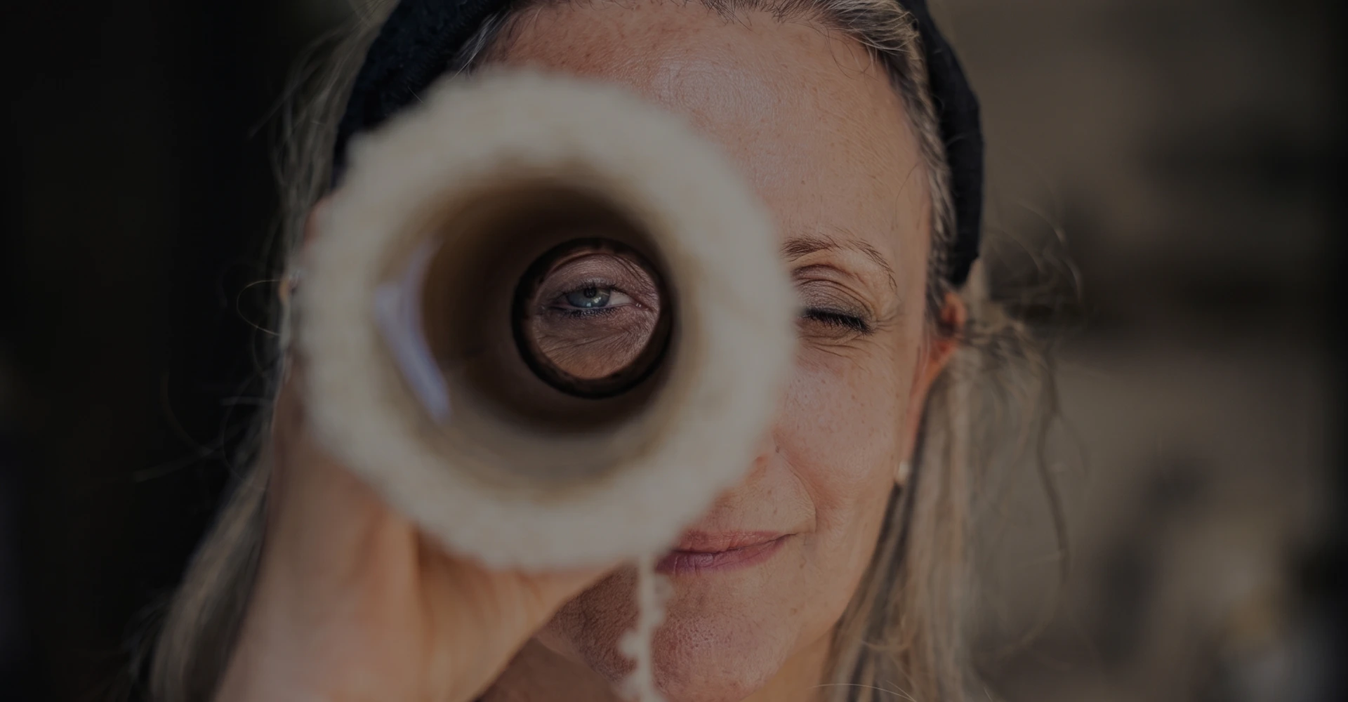 Close-up of Mariella playfully peering through a white paint roller like a telescope.