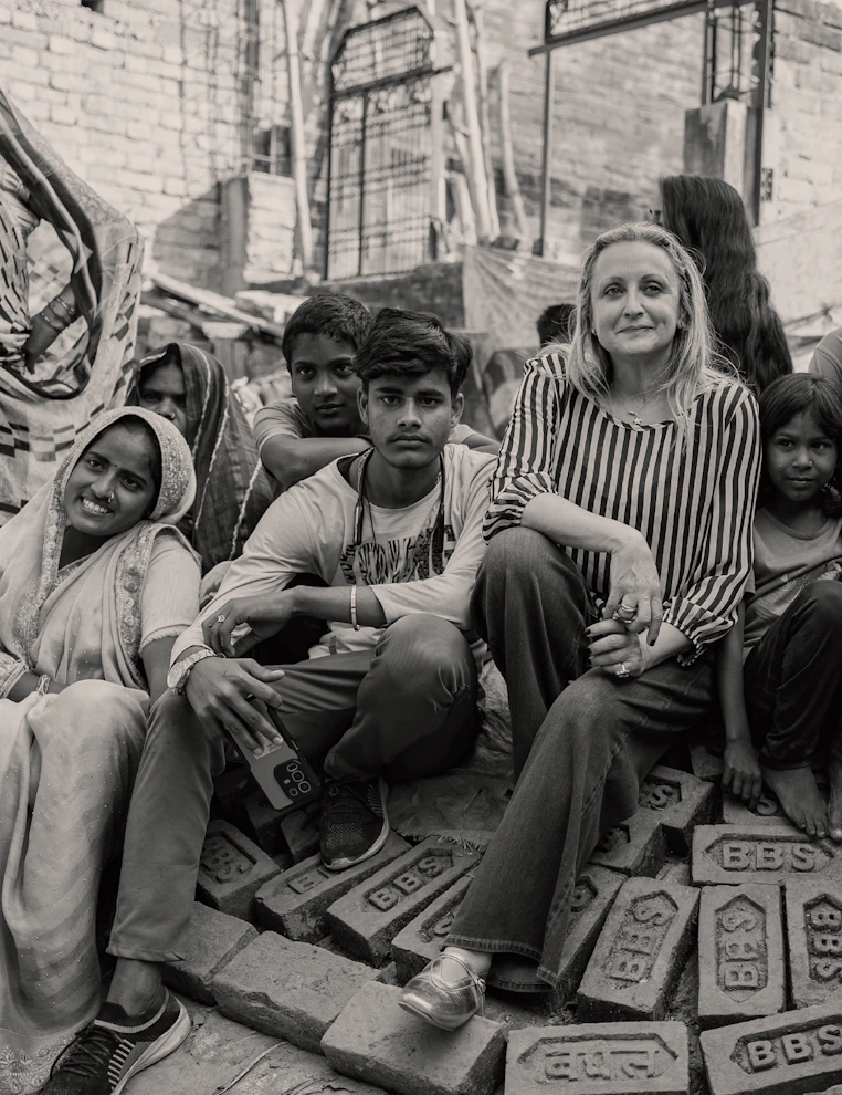 Group sitting on piles of stamped bricks at a rustic site, looking toward the camera.