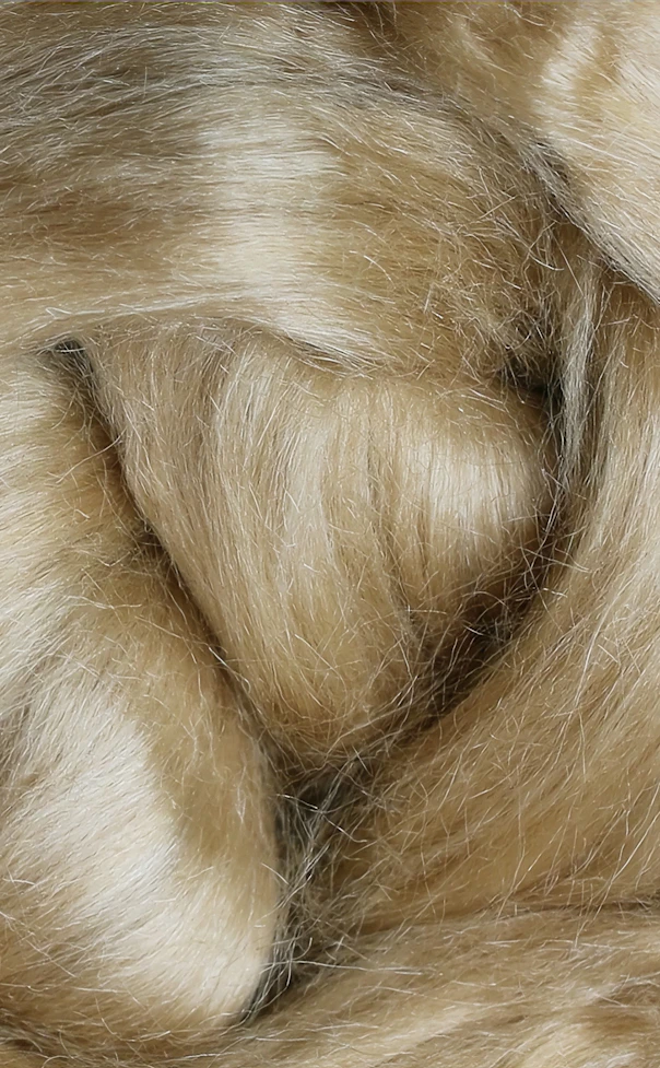 Close-up of soft cream and beige faux fur or dense fiber, folded into gentle rippling waves.
