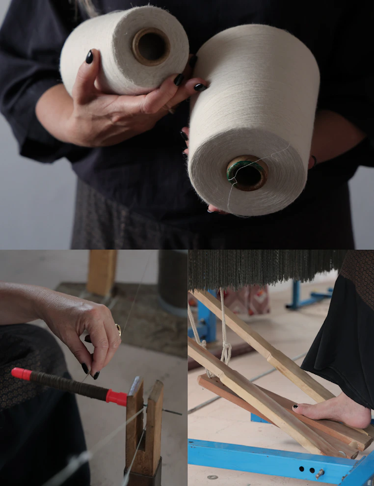 Person holding two large spools of off white yarn, tool and foot operating a loom.