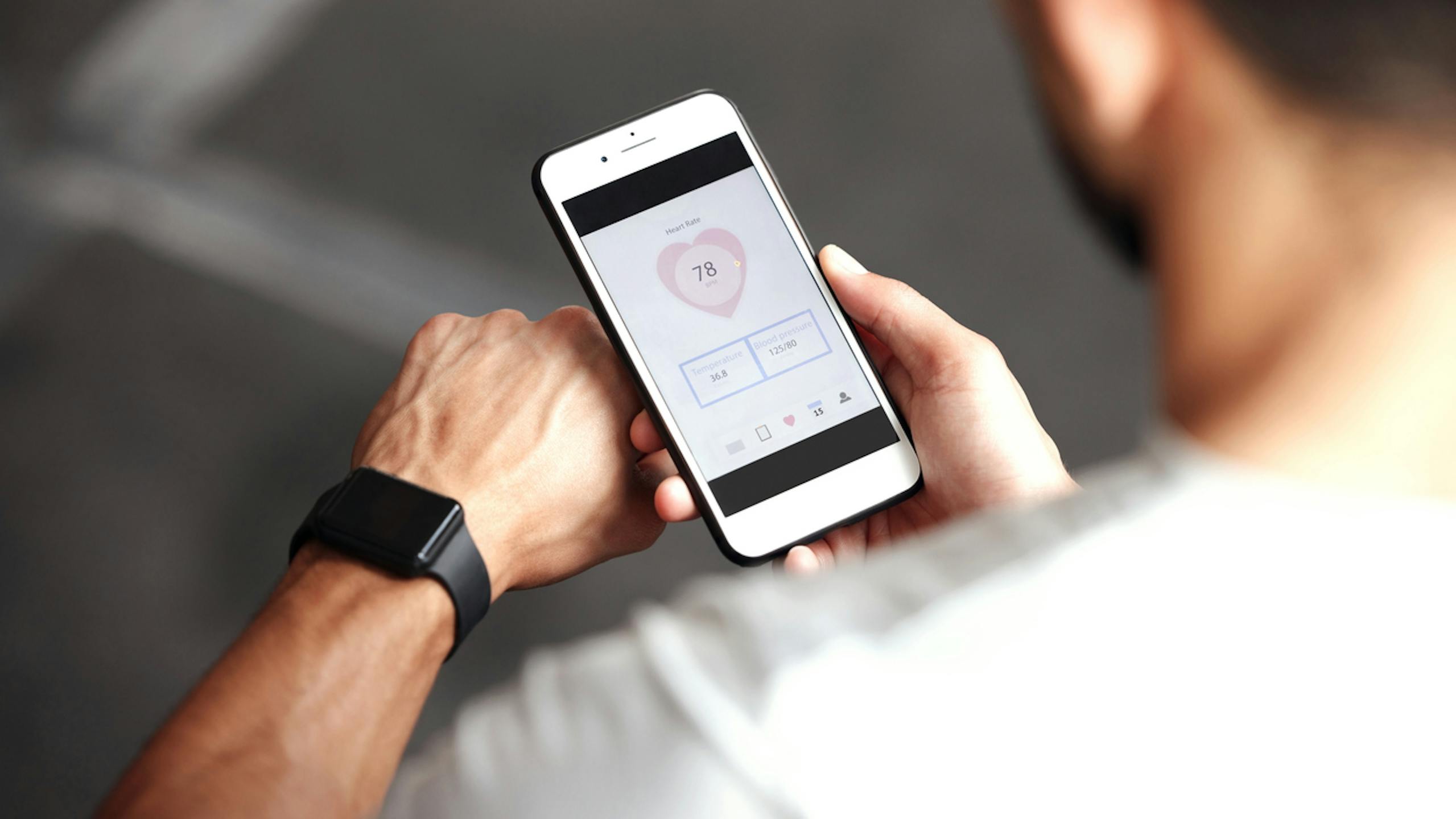 Gros plan d’un homme vérifiant des applications de santé sur une montre connectée et un téléphone portable pour faire de l’exercice