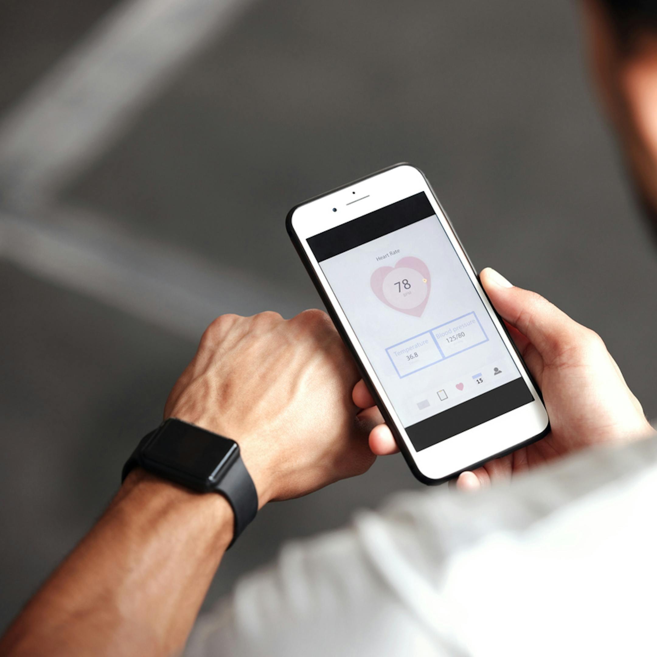 Gros plan d’un homme vérifiant des applications de santé sur une montre connectée et un téléphone portable pour faire de l’exercice