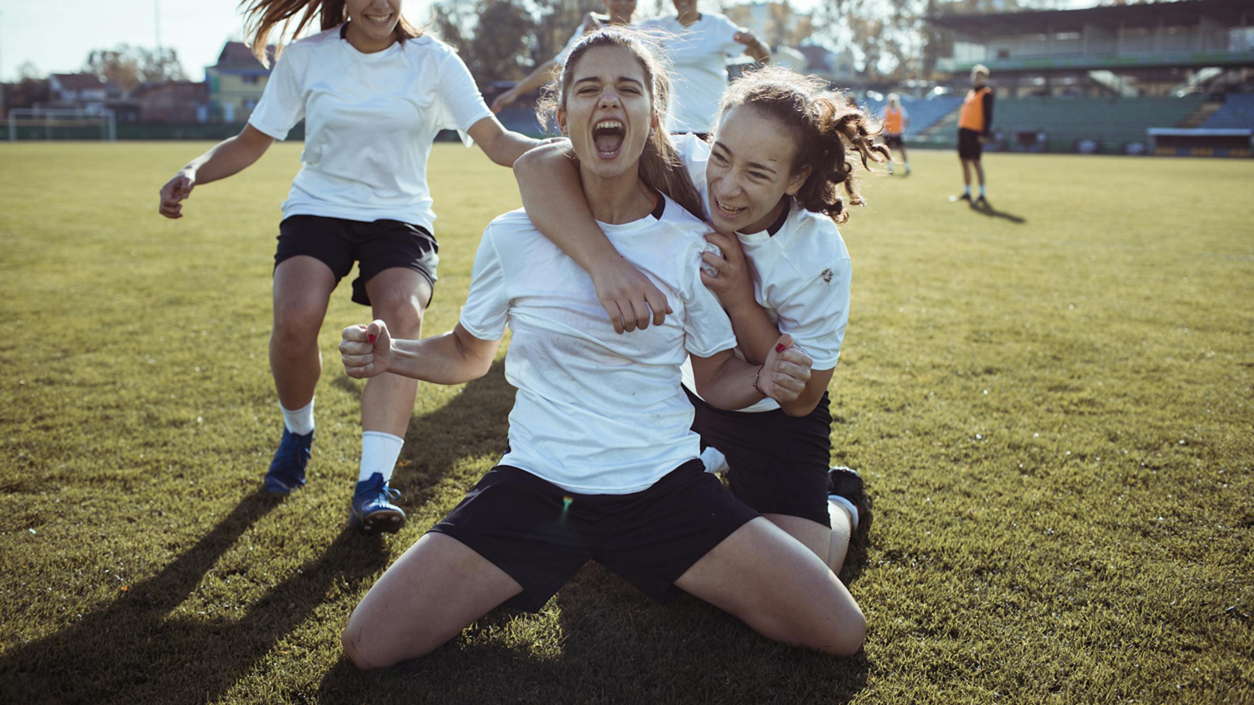 Jeunes footballeuses célébrant leur victoire sur un terrain de foot