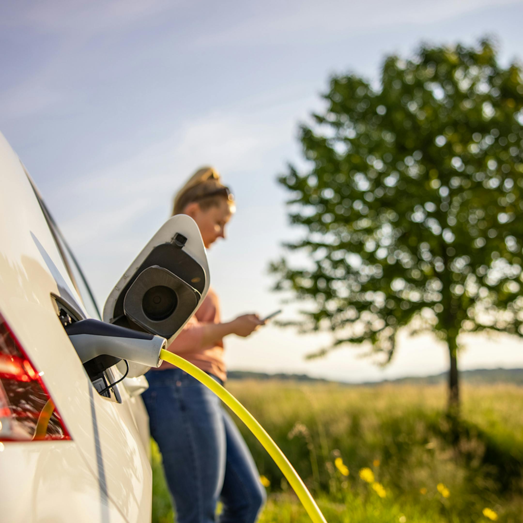 Jeune femme attendant que sa voiture éléctrique charge