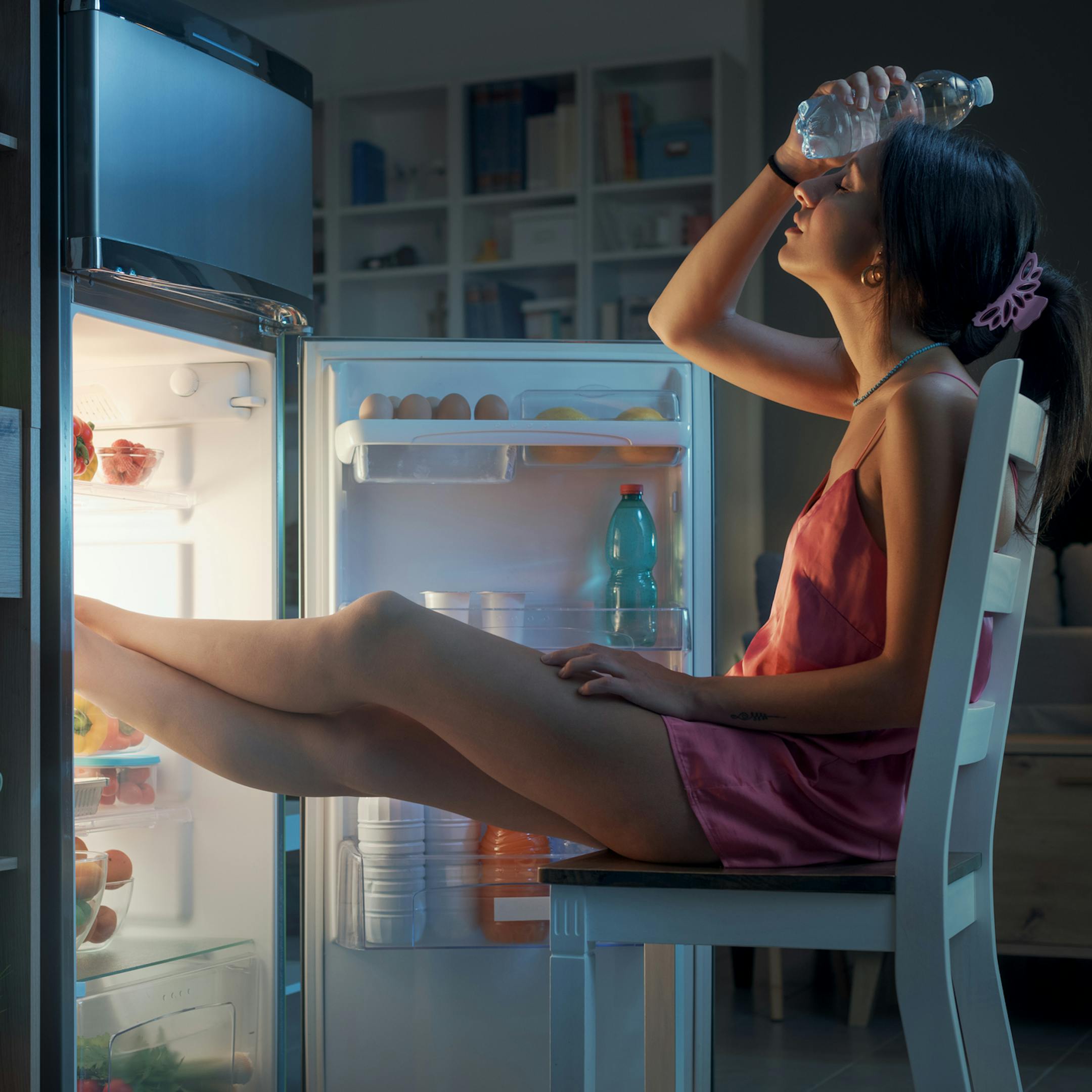 Femme se refraichissant devant son frigo
