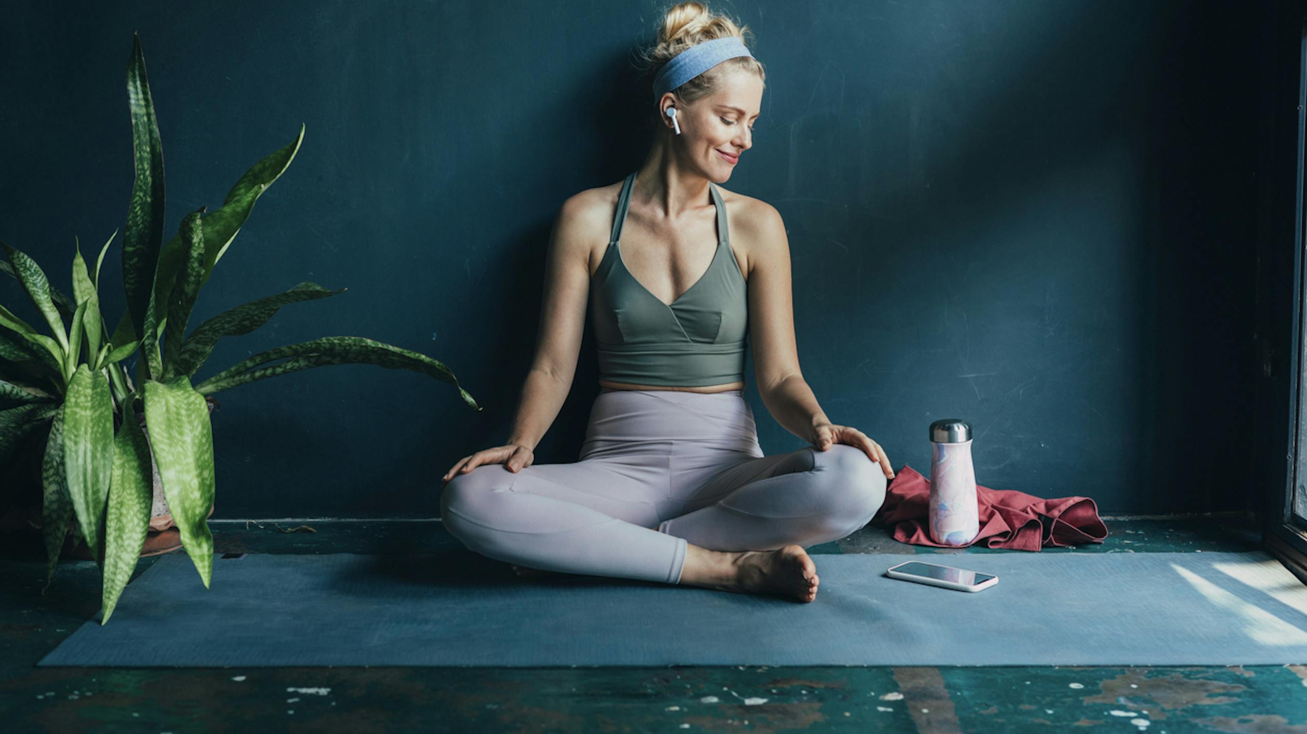 Jeune femme s'apprêtant à faire son cours de yoga dans un studio épuré