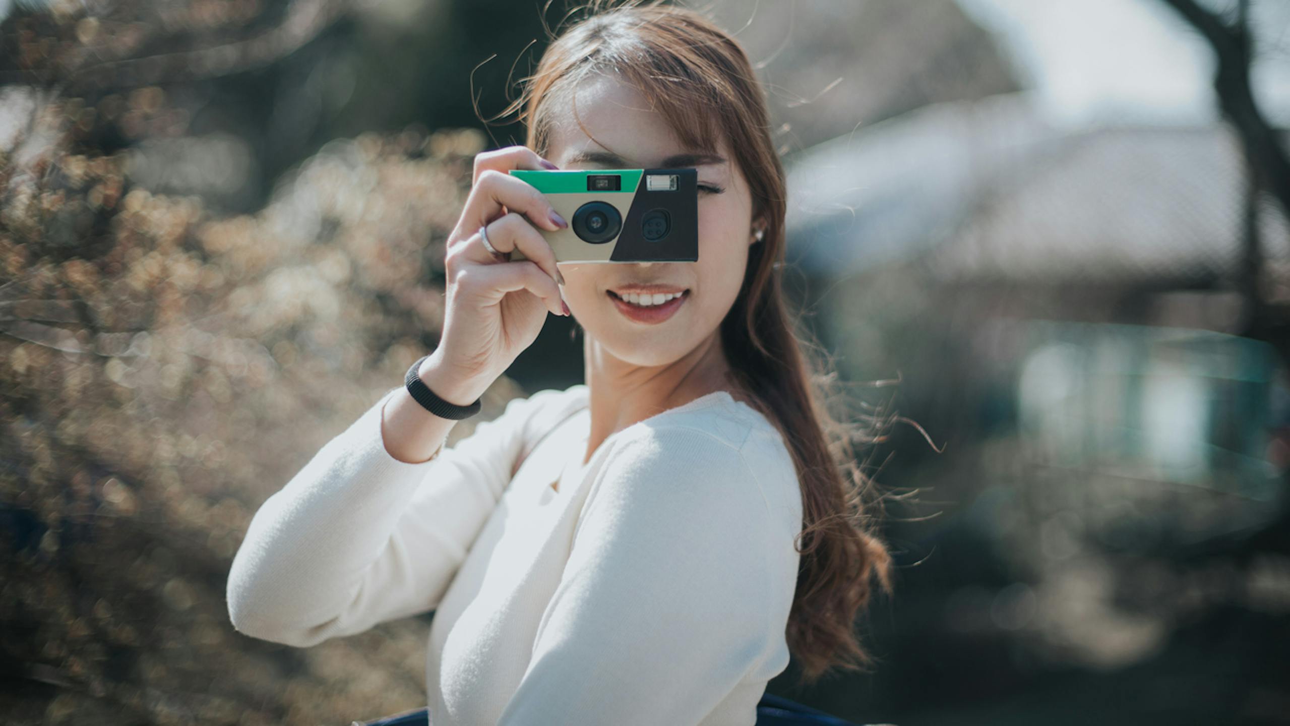 Jeune femme prenant des photos avec la caméra jetable dans un parc par une belle journée ensoleillée 