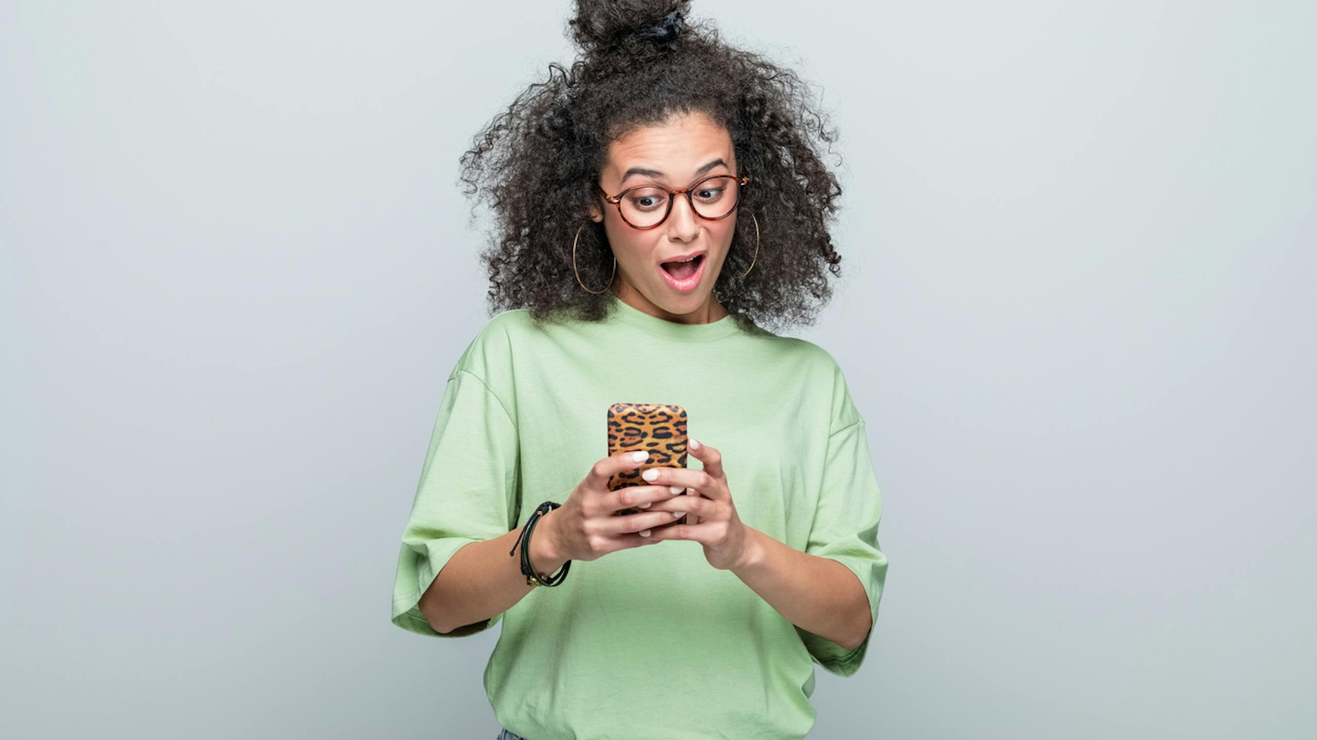 Portrait d’une jeune femme surprise utilisant un téléphone