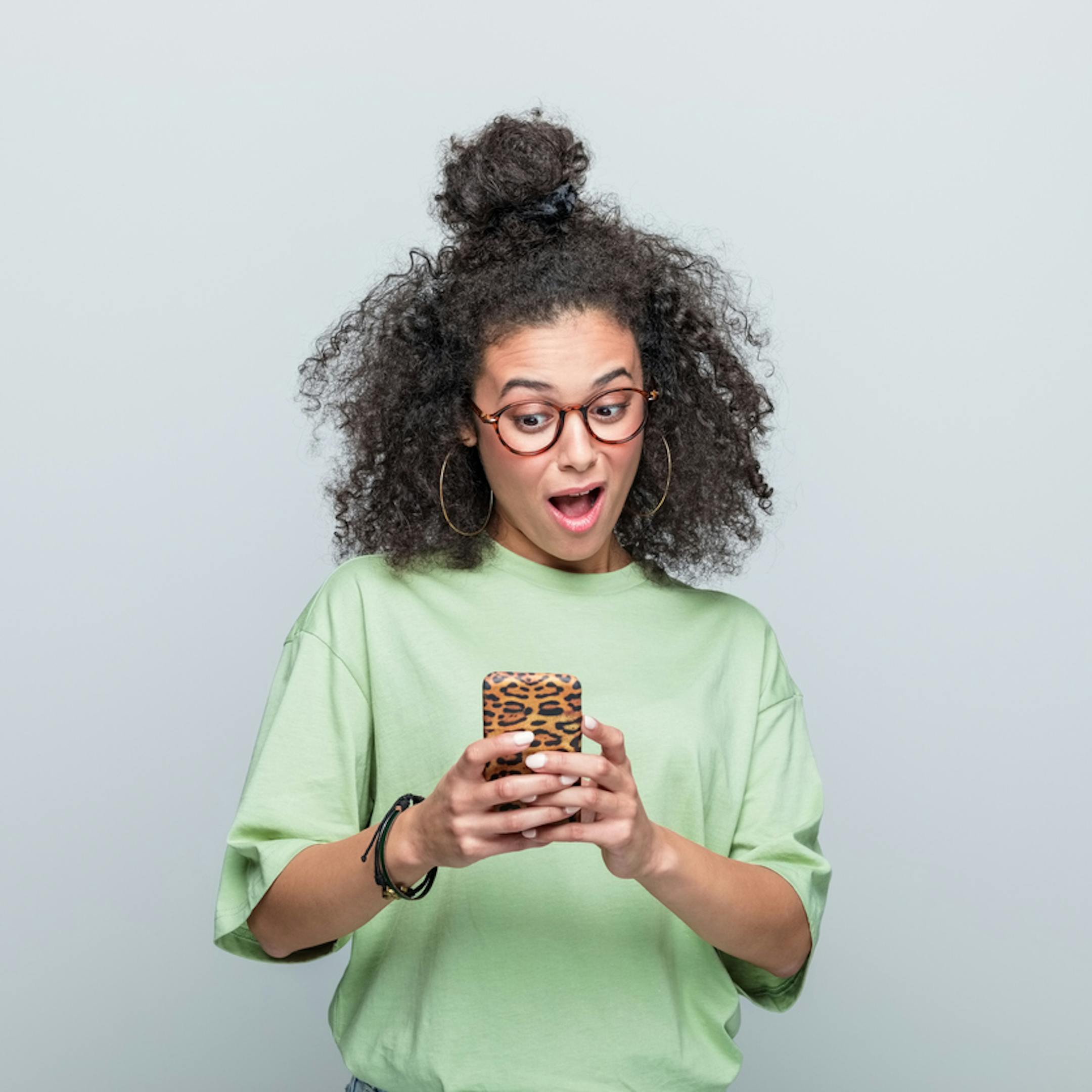 Portrait d’une jeune femme surprise utilisant un téléphone