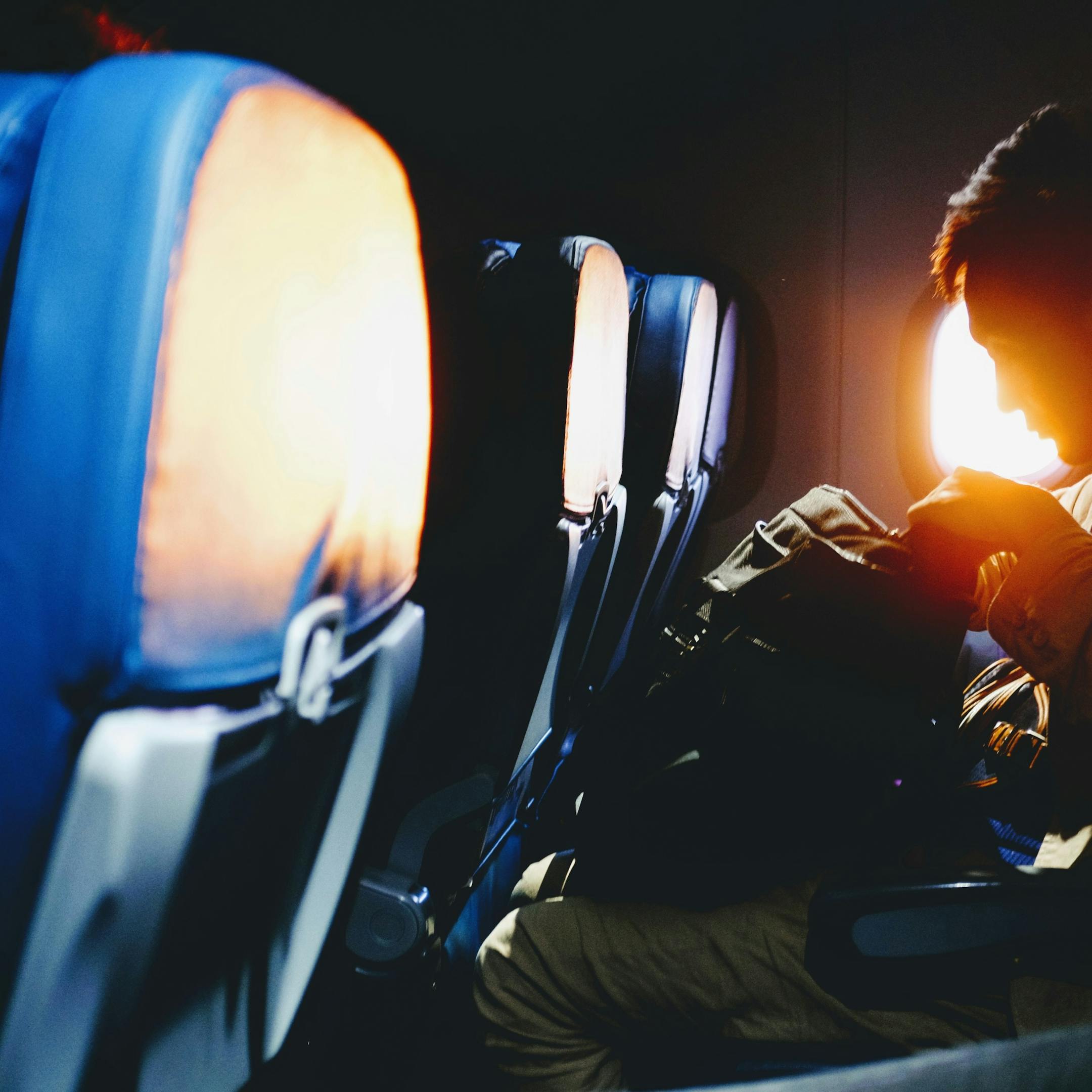 Jeune homme assis près du hublot dans un avion voyageant avec un seul sac à dos
