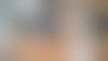 Deux personnes attablées devant un ordinateur et une tablette dans leur salon sont en train de gérer leurs factures.