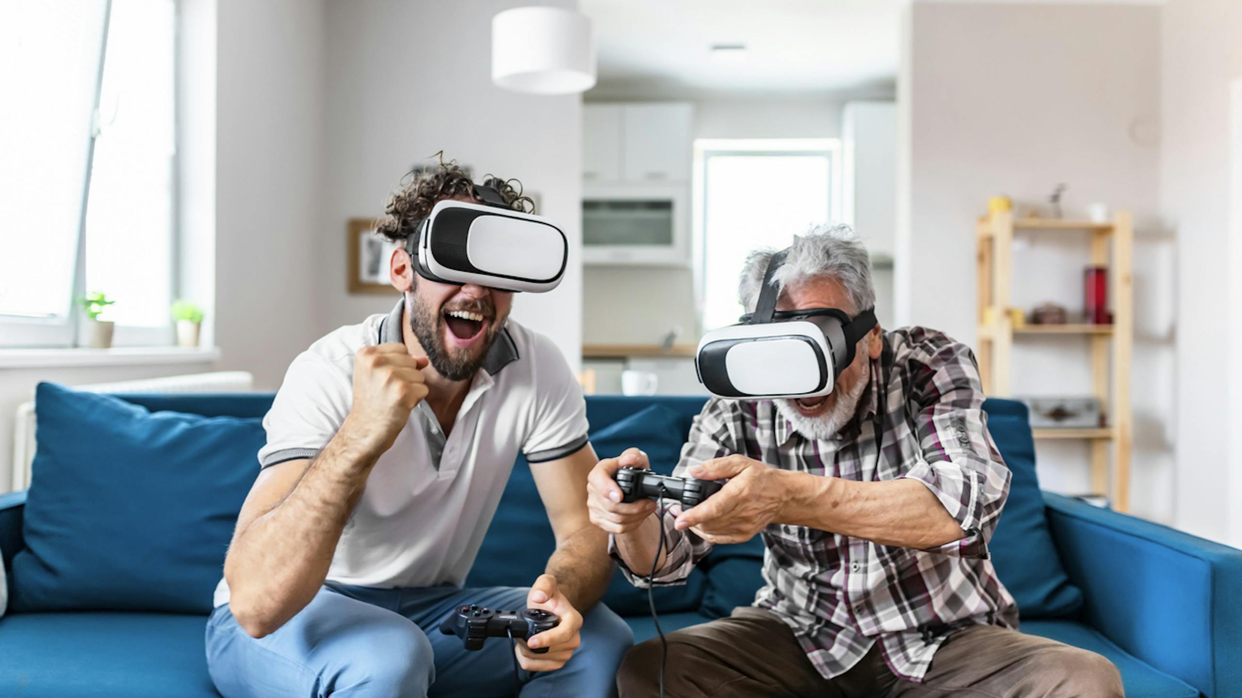 Père et fils dans les casques de VR jouant des jeux vidéo sur le divan à la maison