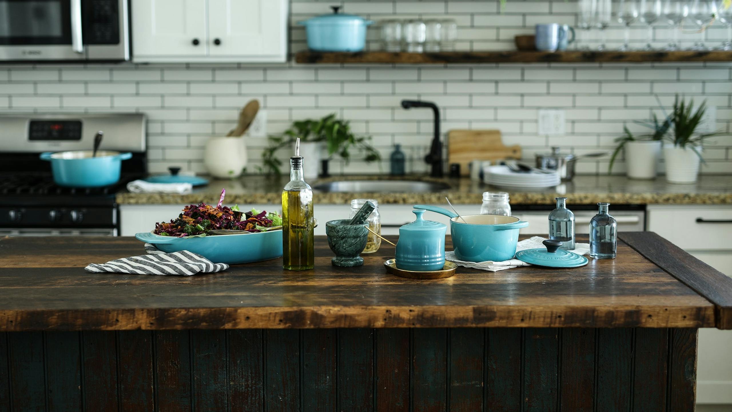 Image d'une cuisine avec des plats et de l'huile d'olive posés sur une table. 