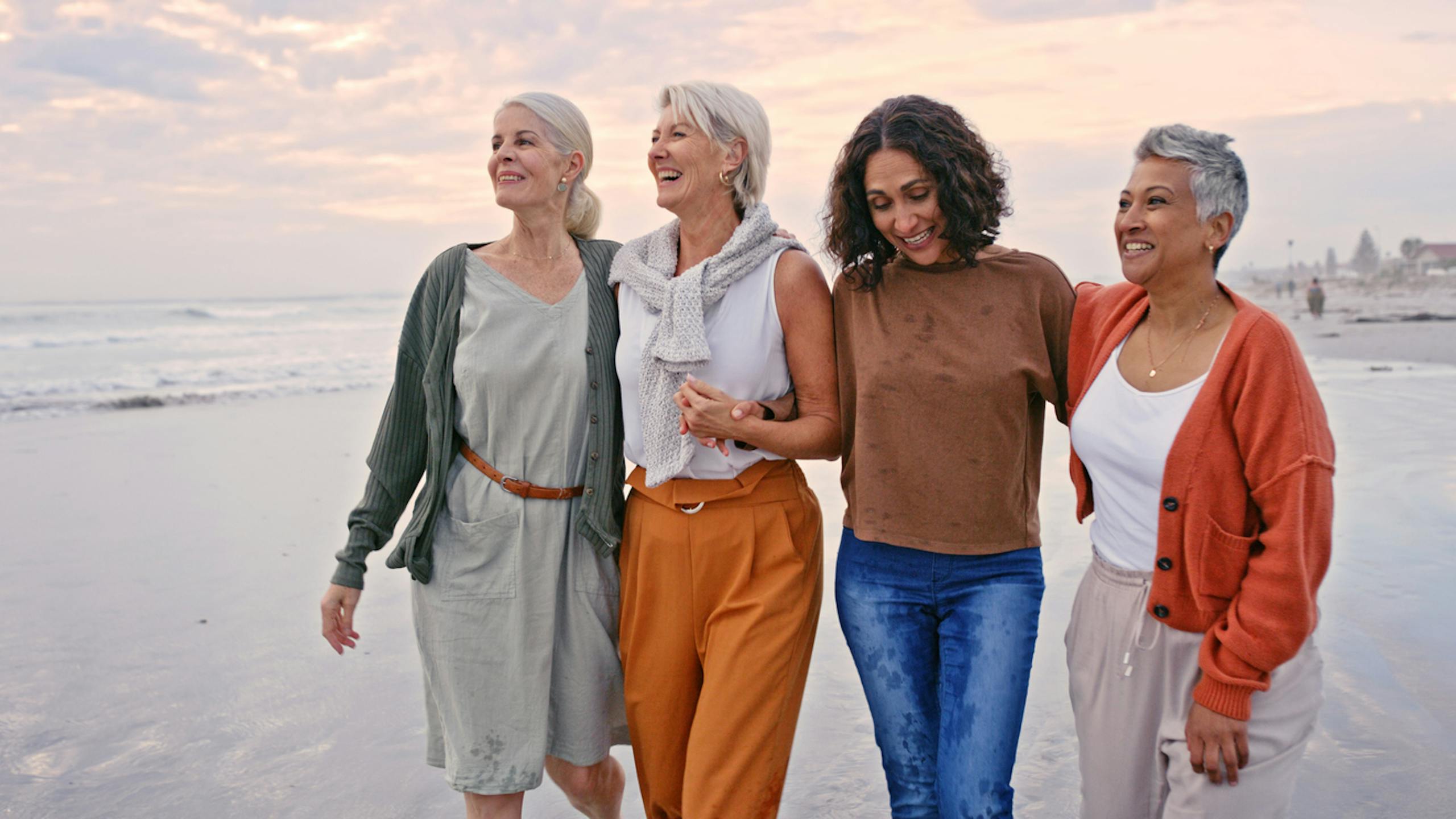 Un groupe de femmes marchant sur le sable au bord de l’océan.