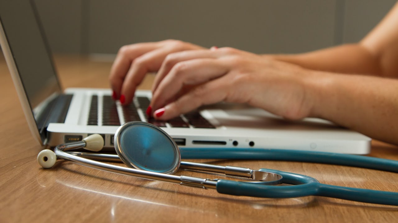 laptop and stethoscope being used by a healthcare provider