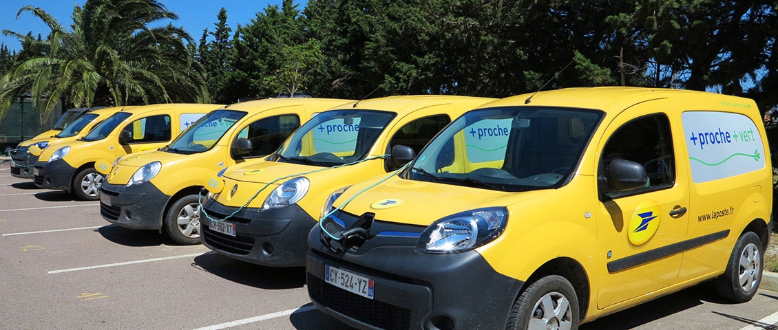 Cinq Kangoo Ze de La Poste en charge sur un parking