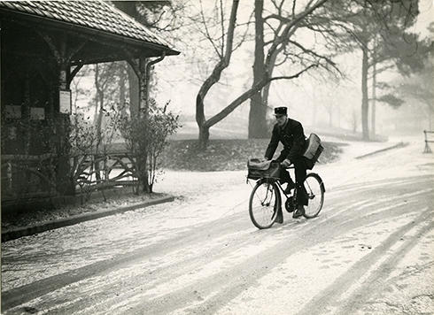 Photo en noir et blanc d'un facteur en tournée à bicyclette, vers 1950