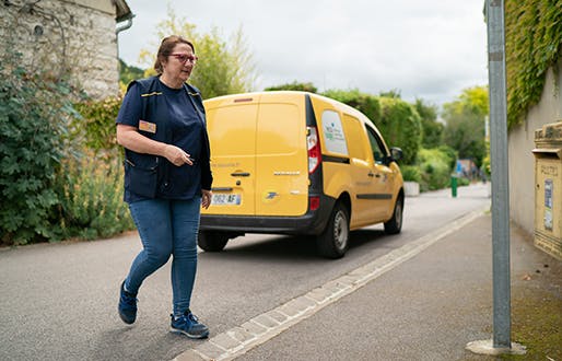 factrice devant une boite aux lettres