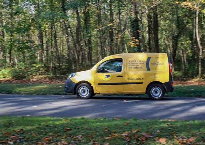 Véhicule électrique de La Poste devant des arbres