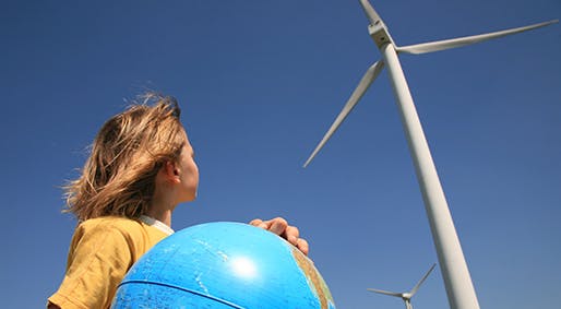 petite fille tient un globe et regarde en haut vers une éolienne