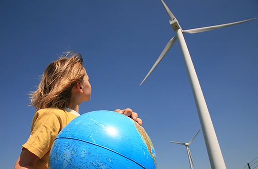 little girl holding a globe and looking up to the windmill