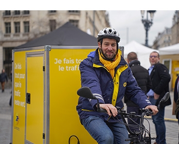 Photo d'un postier sur un vélo cargo, en ville