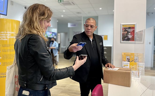 photo d'un postier et d'une cliente en bureau de Poste