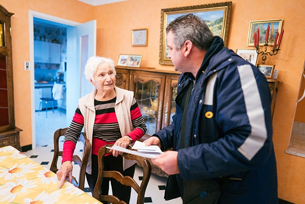 un facteur rend visite a une personne agée