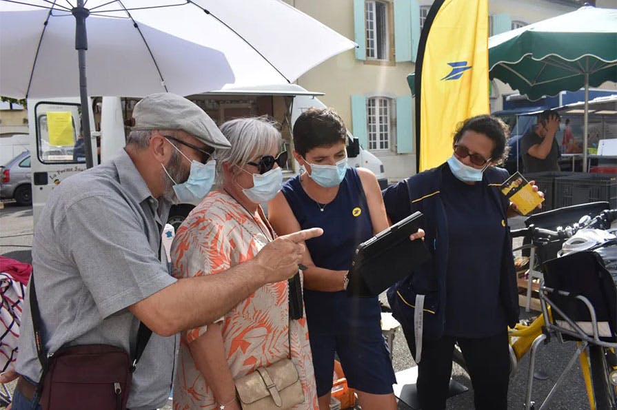 Sur le marché de Navarrenx, la factrice explique l'usage de la tablette Ardoiz