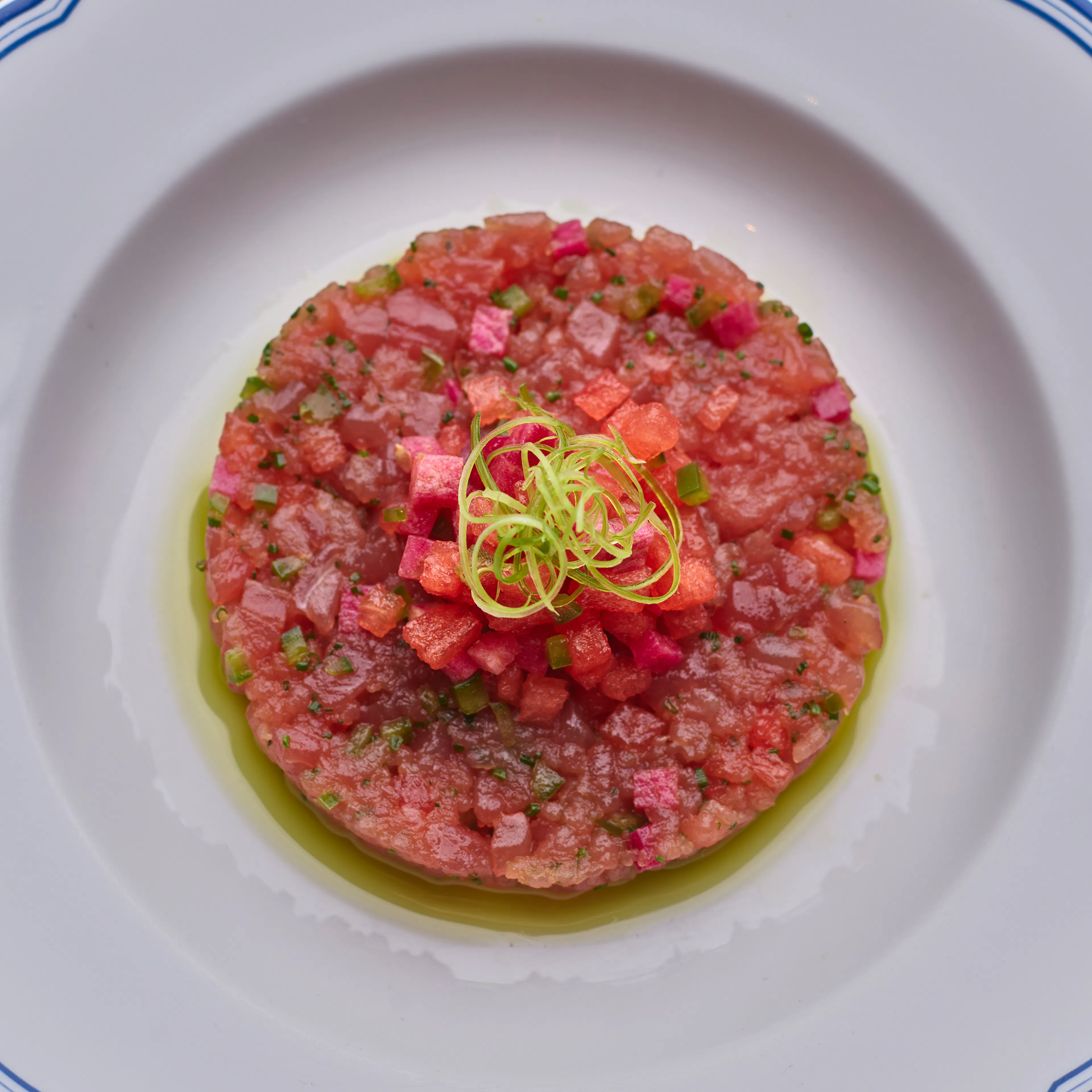 Yellowfin tuna tartare with watermelon, radish, and lemon verbena, artfully plated with fresh seasonal garnishes.